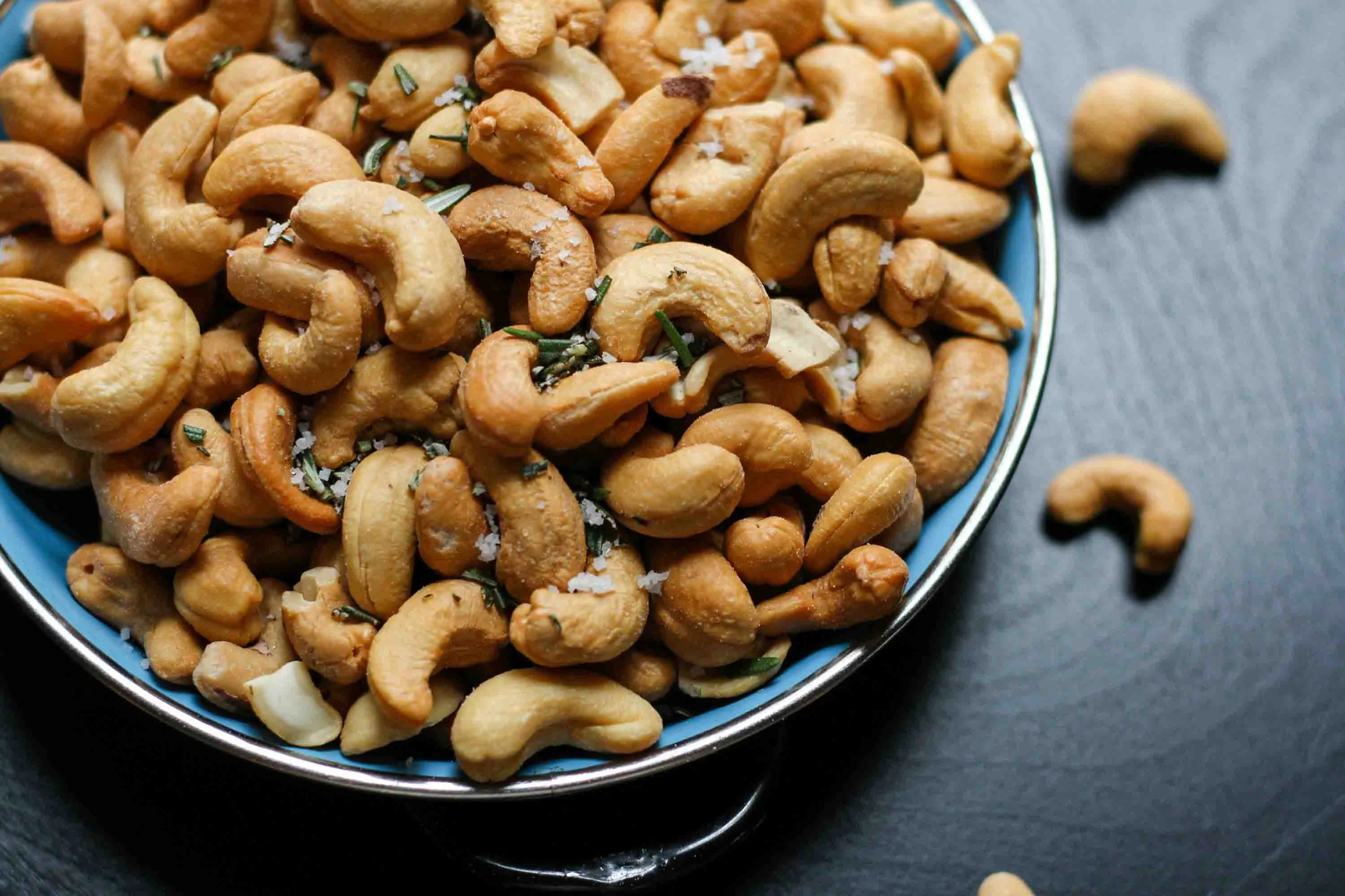 A bowl of roasted cashews, a magnesium-rich snack, supporting the activation of vitamin D3 (cholecalciferol) for optimal bone health and immune function.