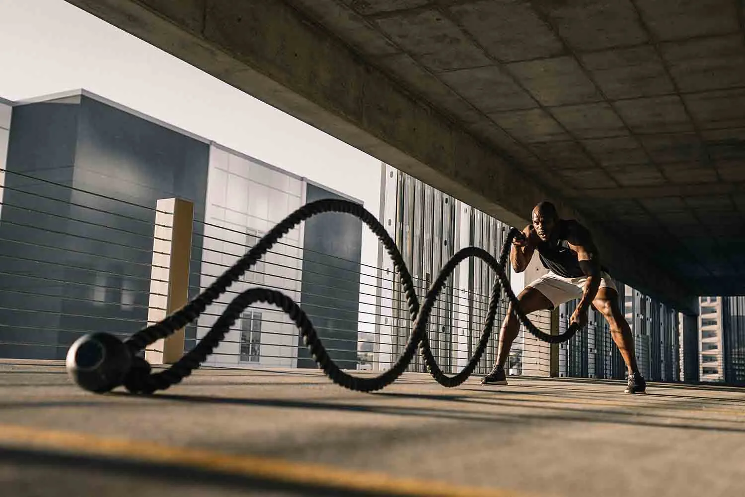A man performing intense battle rope exercises in an urban setting, illustrating how strength training can naturally boost testosterone levels.
