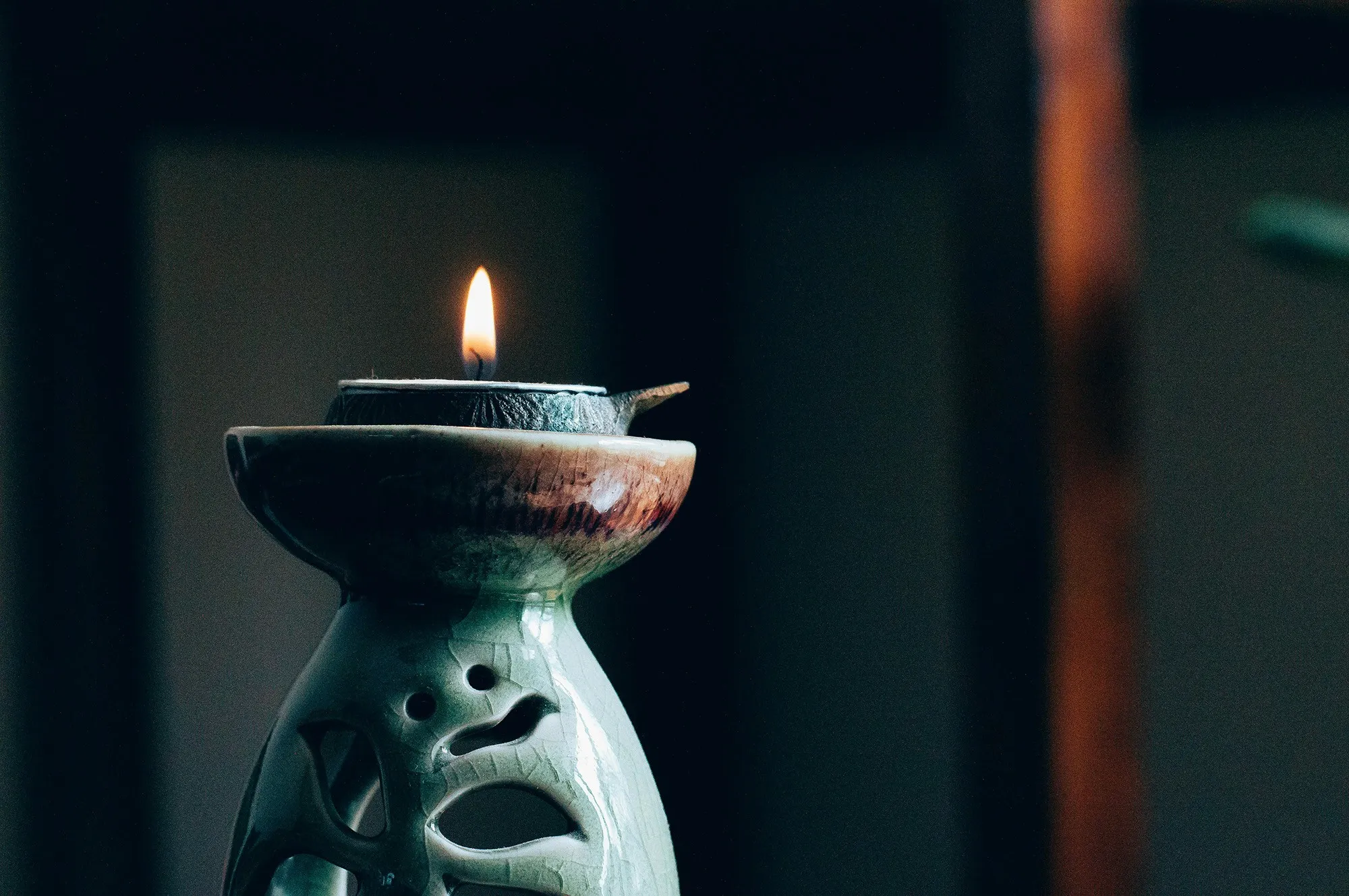A small candle burner with a single flame, symbolizing a calming ritual or mindful meditation practice before sleep.