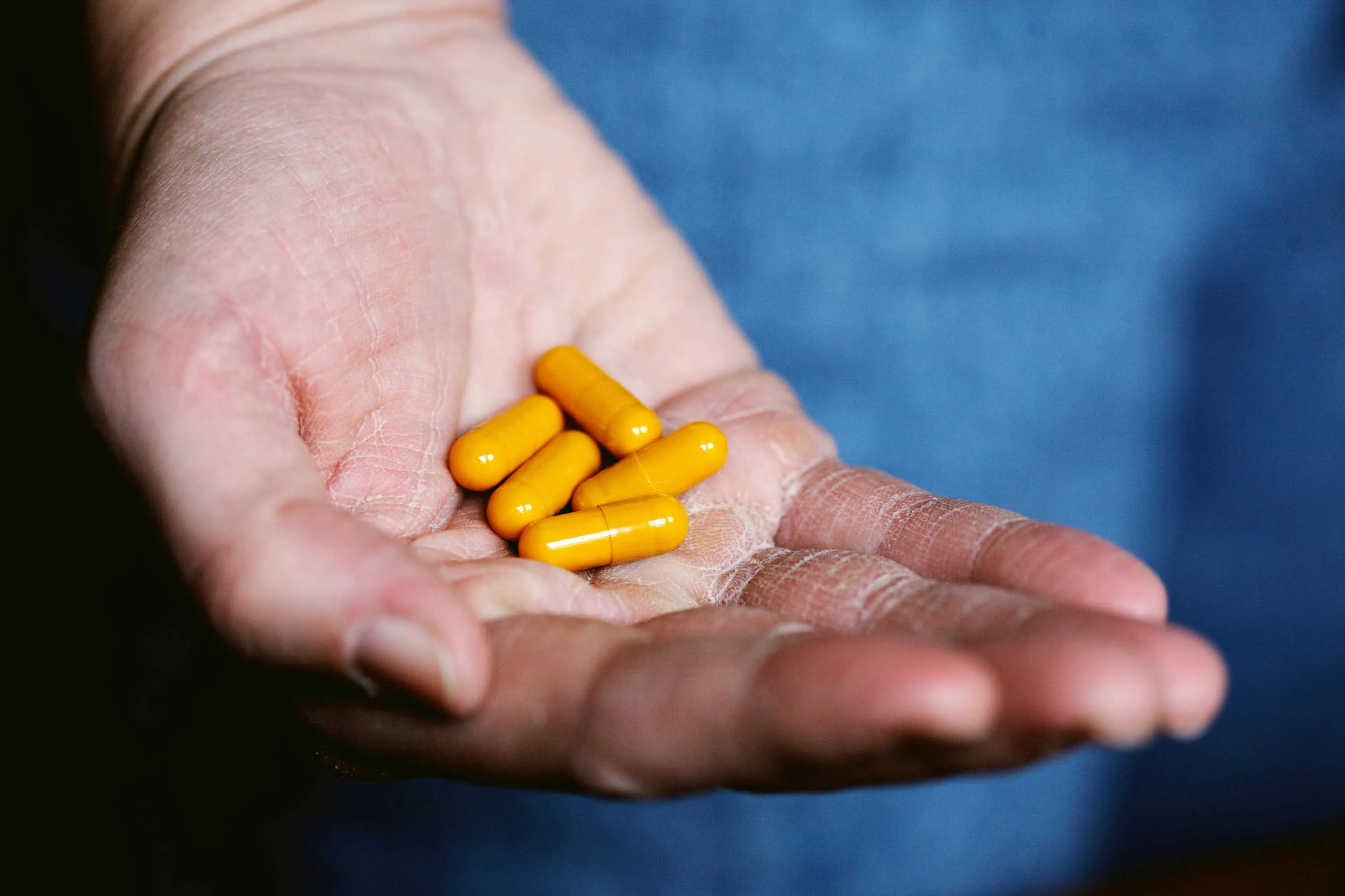 An open palm holding bright yellow vitamin D3 and K2 capsules, illustrating how their synergy—alongside magnesium—supports bone health, calcium regulation, and overall wellness.