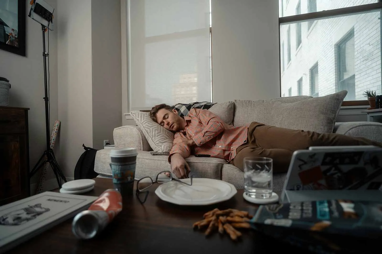 A man napping on a couch in a bright living room, emphasizing the critical role of quality sleep in maintaining optimal testosterone levels.