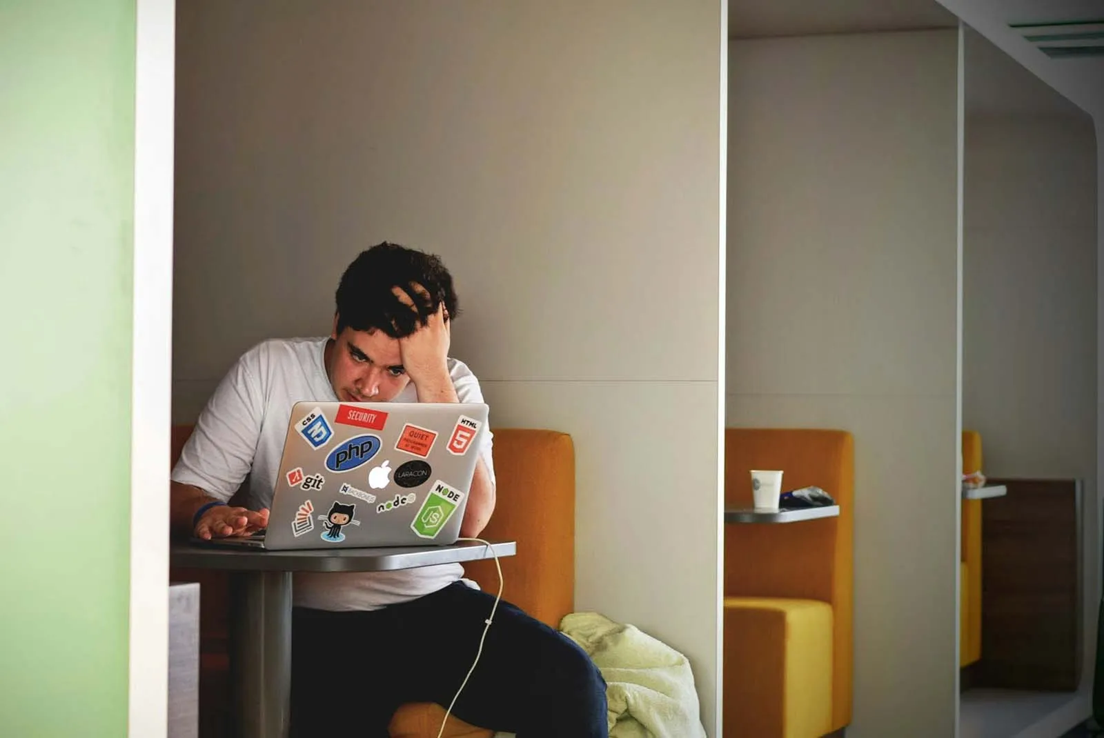 A man hunched over his laptop with his head in his hand, highlighting how chronic stress and elevated cortisol can reduce testosterone production.